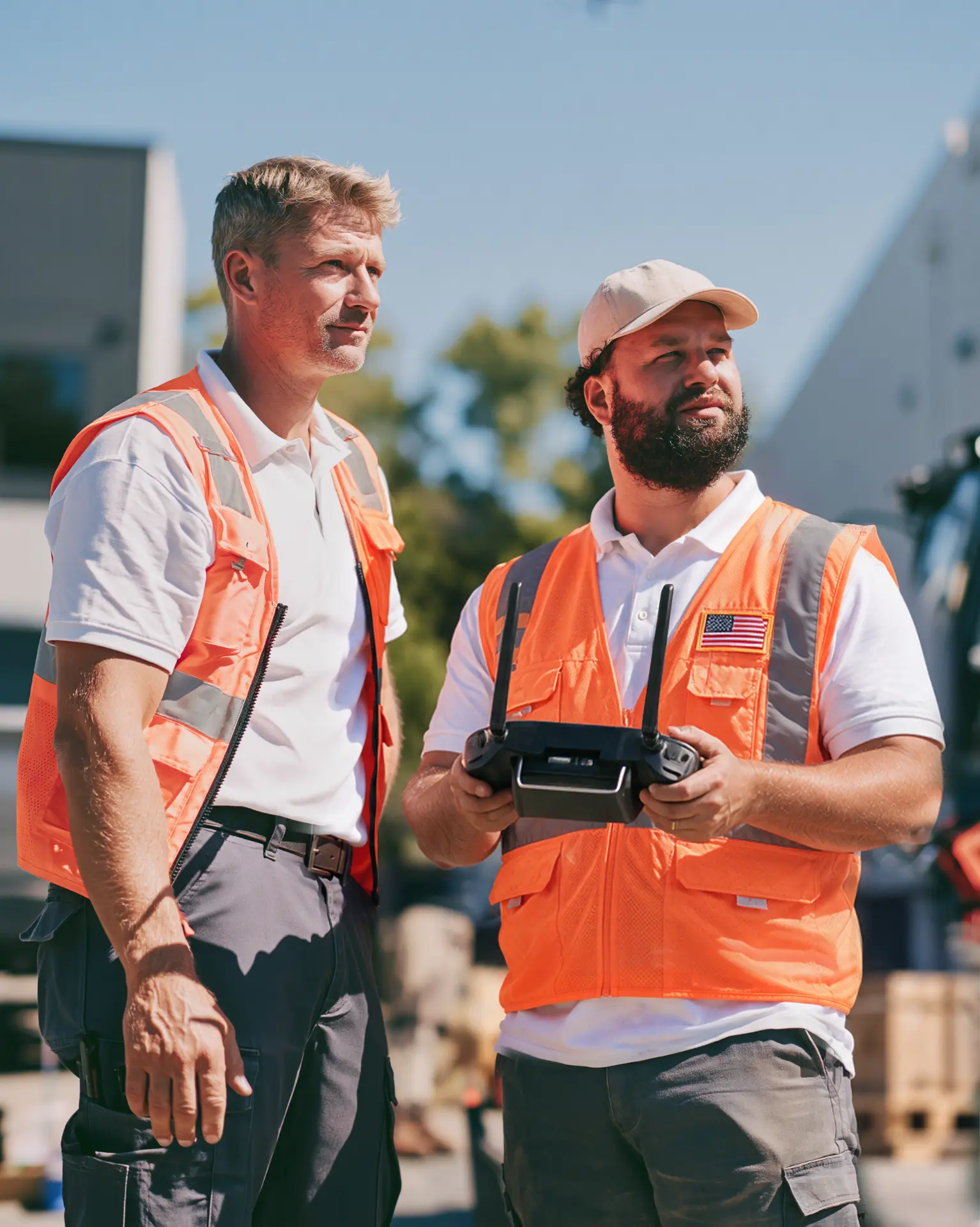 Two drone pilots in safety vests operating a ground control station