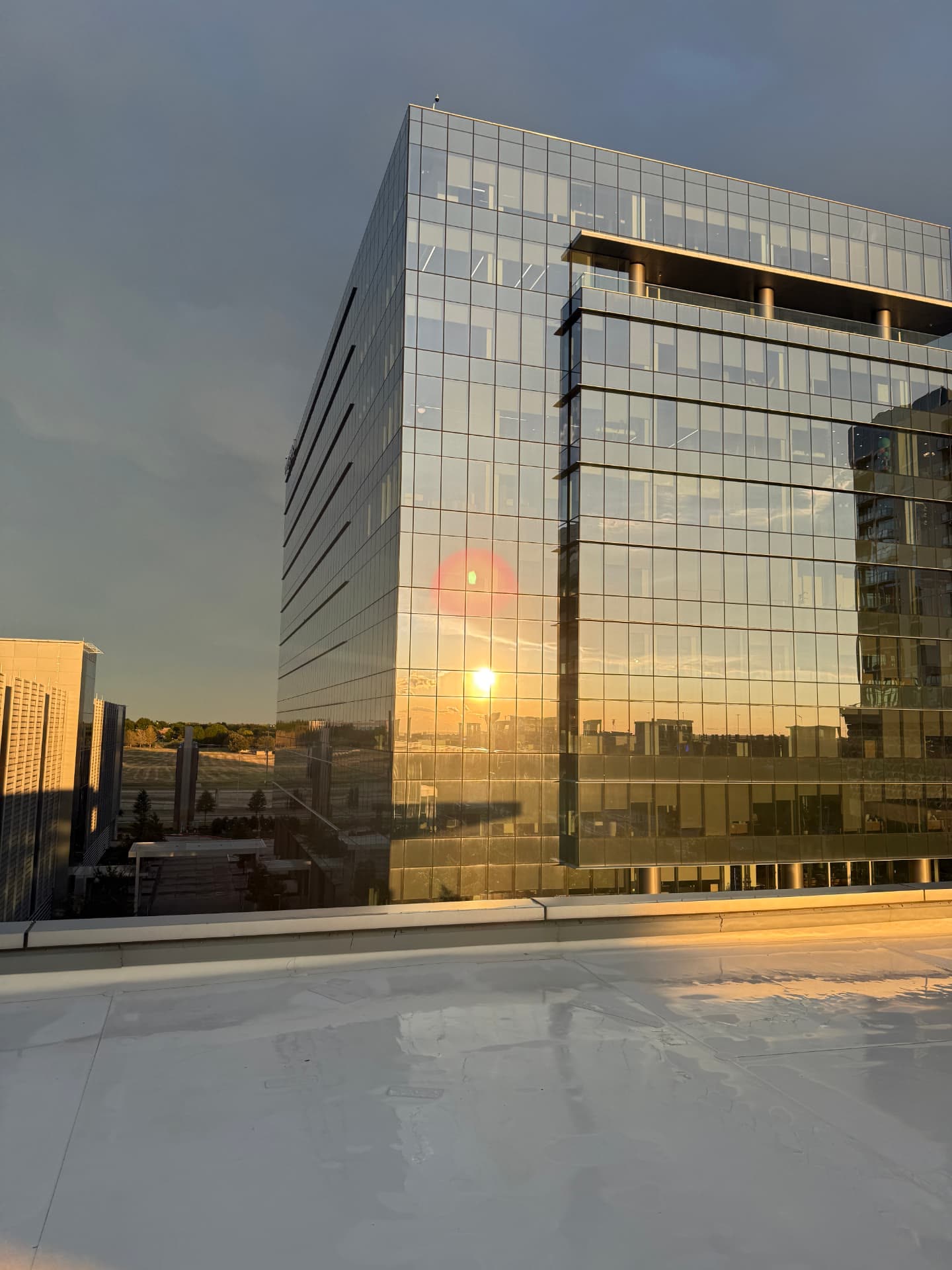 Reflective glass office tower photographed from an adjacent rooftop