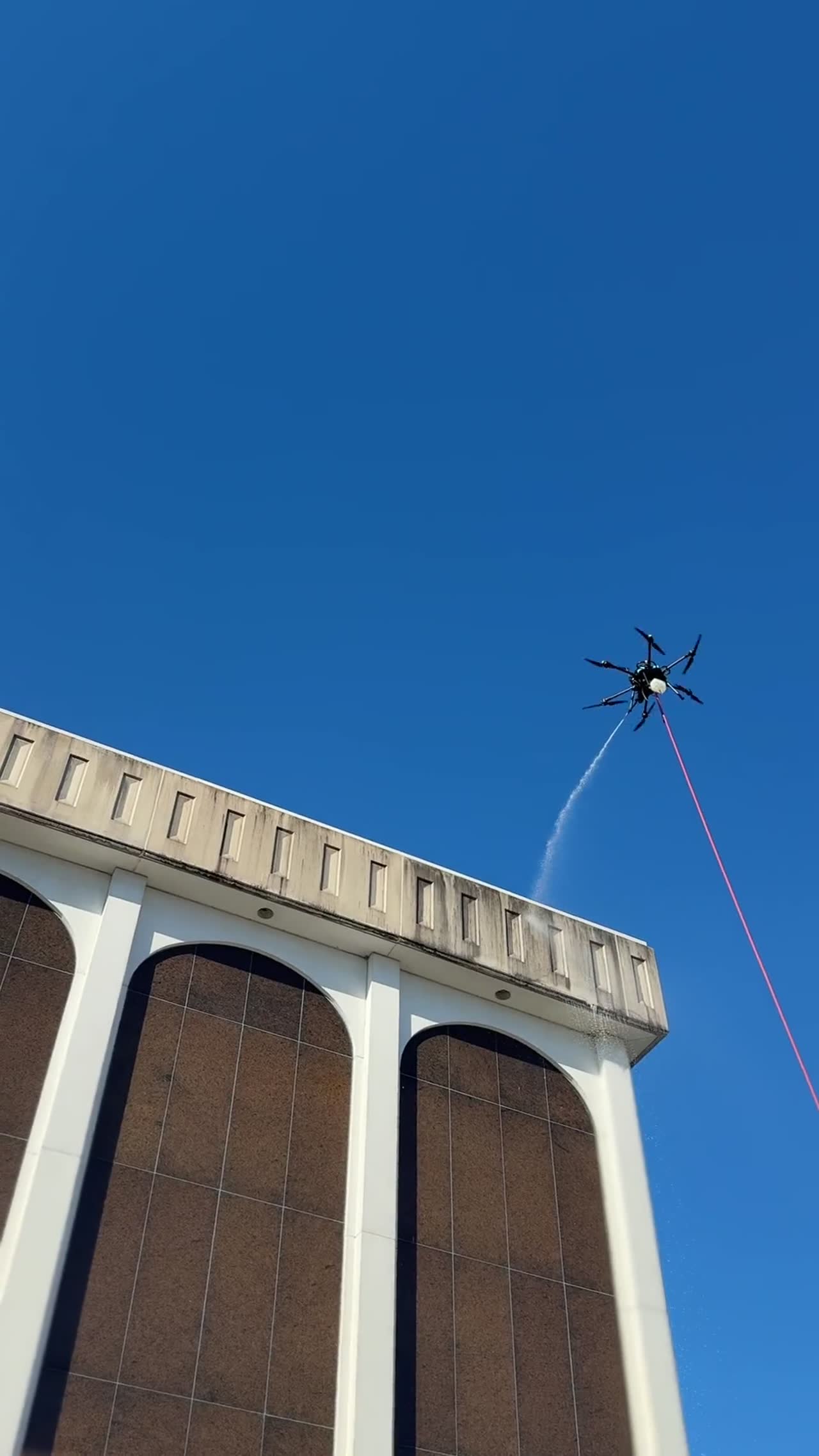 Drone rinsing the concrete cornice of a mid-century commercial building