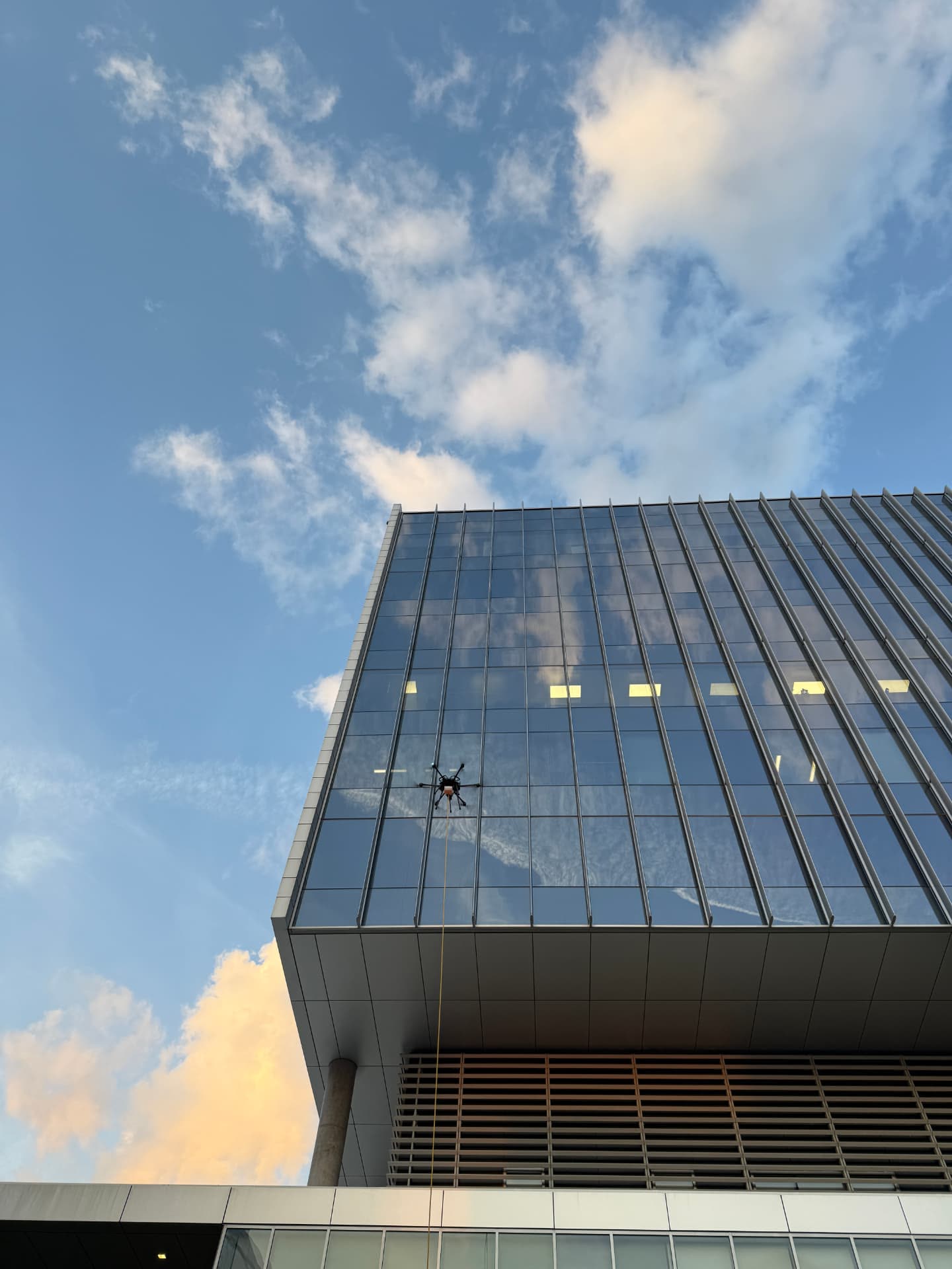 Drone cleaning the glass curtain wall of a modern office tower