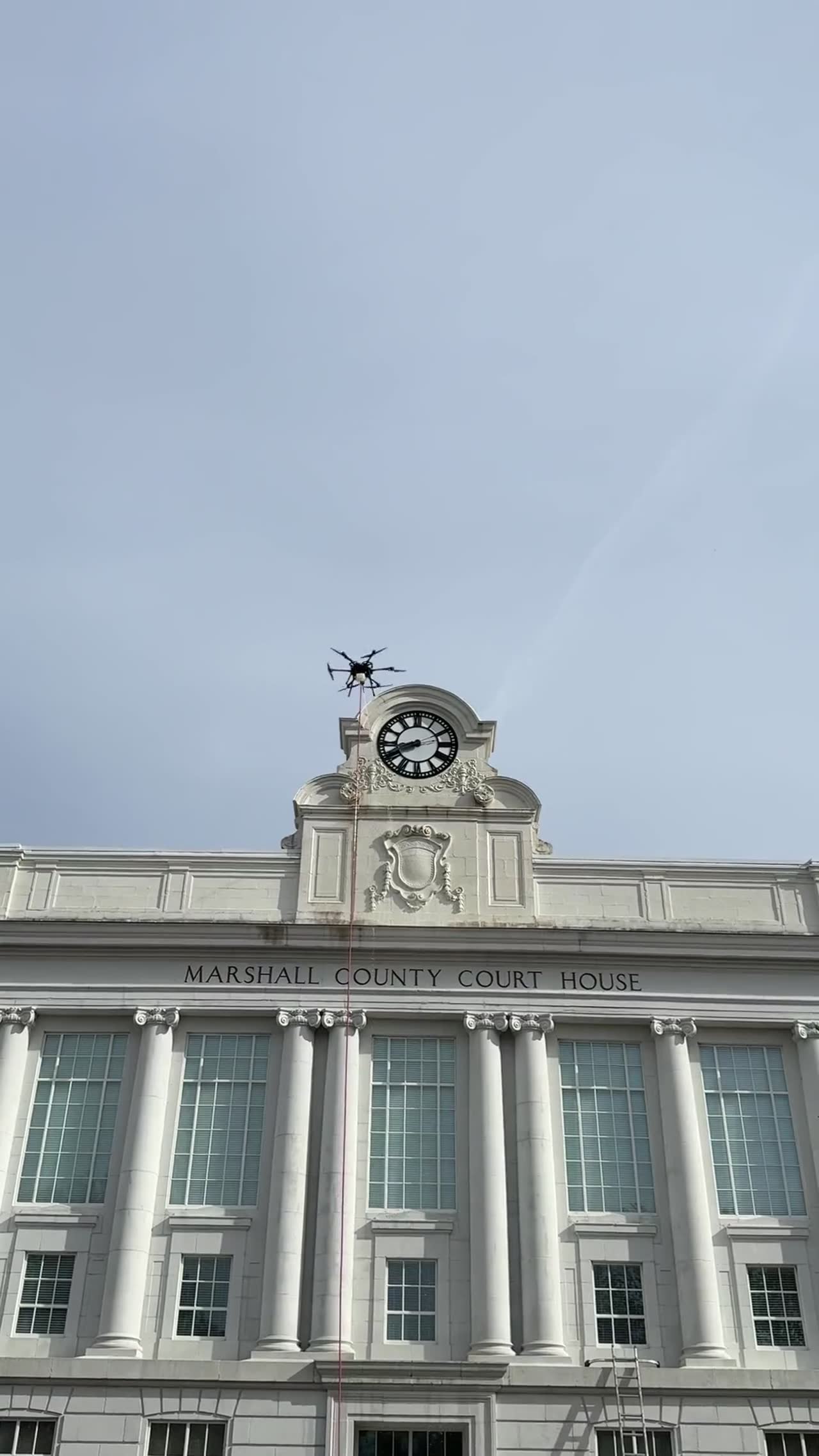 Drone cleaning the clock tower of a historic courthouse